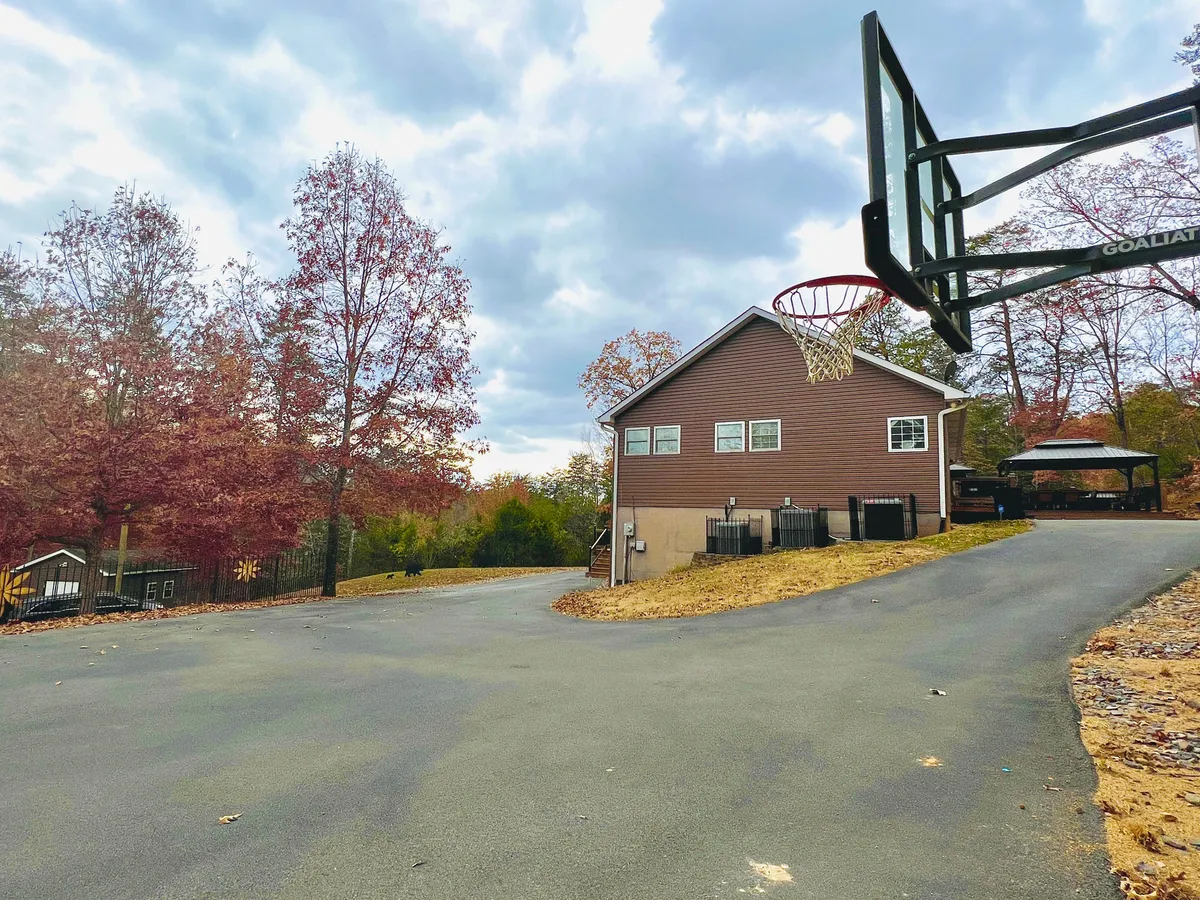 A clear view of the house's exterior with a basketball hoop out front, framed by fall foliage and open skies. The scene captures the playfulness and family-friendly spirit of the outdoor amenities.