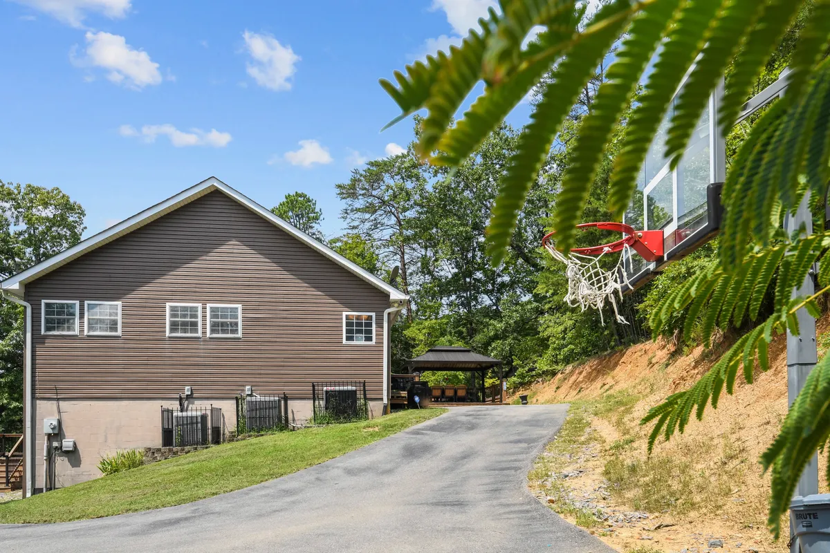 This image features the exterior of the property, with a clear view of the house, a basketball hoop set up in the driveway, and lush surrounding greenery. The scene exudes a sense of energy and outdoor fun, inviting guests to participate in active pursuits right on the property.