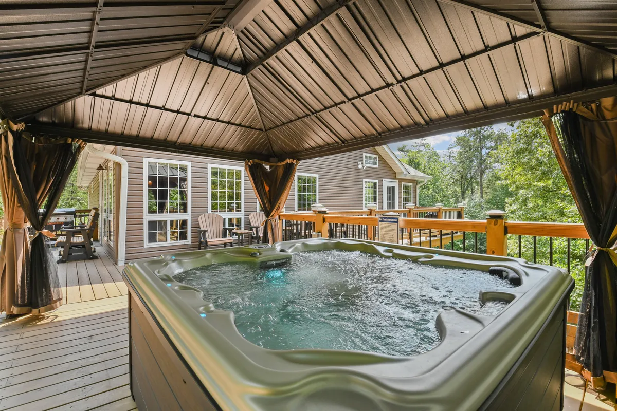 A tranquil outdoor setting featuring a hot tub under a gazebo, nestled within surrounding natural beauty. The space feels private and relaxing, ideal for unwinding after a day of mountain adventure.